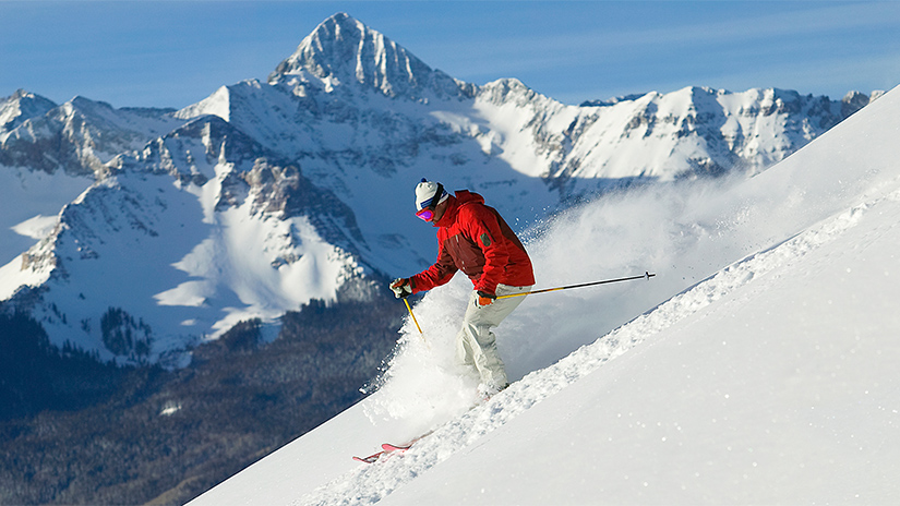 Man in red jacket skiing in Telluride, Colorado with Inspirato.