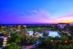 Sunset view overlooking private pools, palm trees, and ocean at Auberge Private Residences at Esperanza in Los Cabos, Mexico.