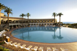 Private, outdoor pool facing the ocean with palm trees at Pelican Hill Resort in Newport Coast.