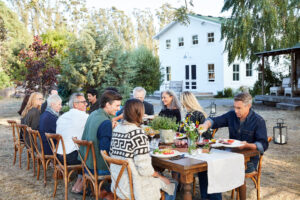 Exclusive vacation club Inspirato members gathered around table enjoying a meal outside together.