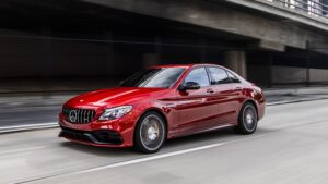 Shiny red sedan Avis car rental driving on freeway.