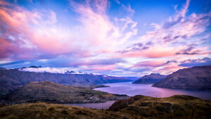 Pink, purple, and blue sunset over New Zealand mountains and lake.