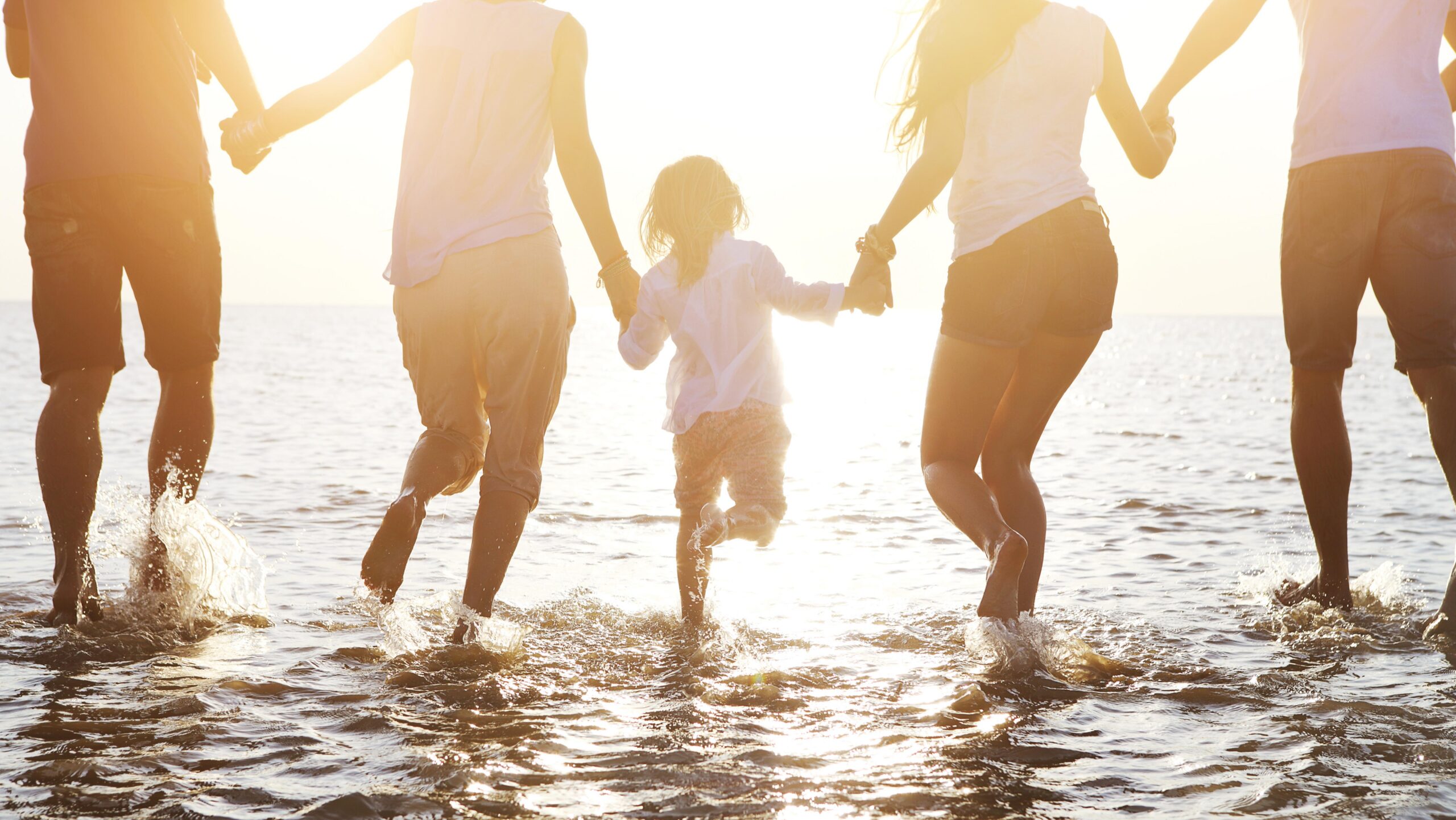 Family of five playing in the ocean while traveling on an Inspirato membership.