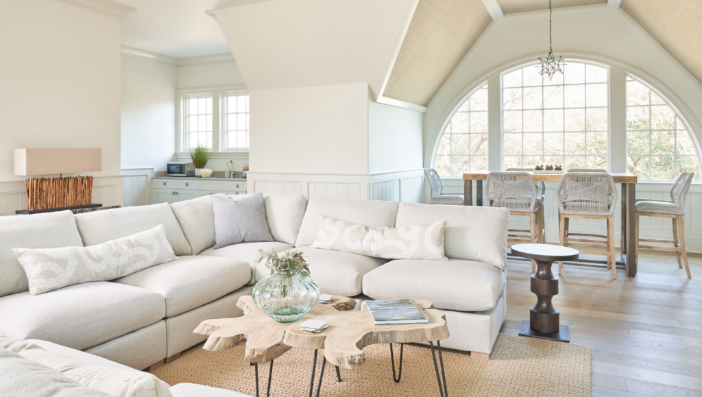 Bright, airy, coastal living area with a white couch and natural wood furniture in an Inspirato home.