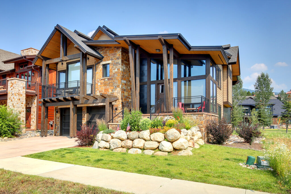 Inspirato modern mountain home in Steamboat Springs, Colorado with wood and red brick front exterior and green lawn.