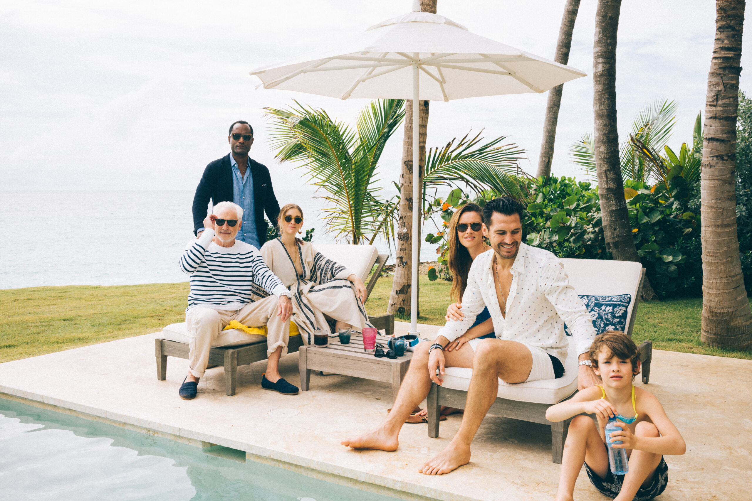 Family sitting poolside at an oceanfront Inspirato home for a family reunion.