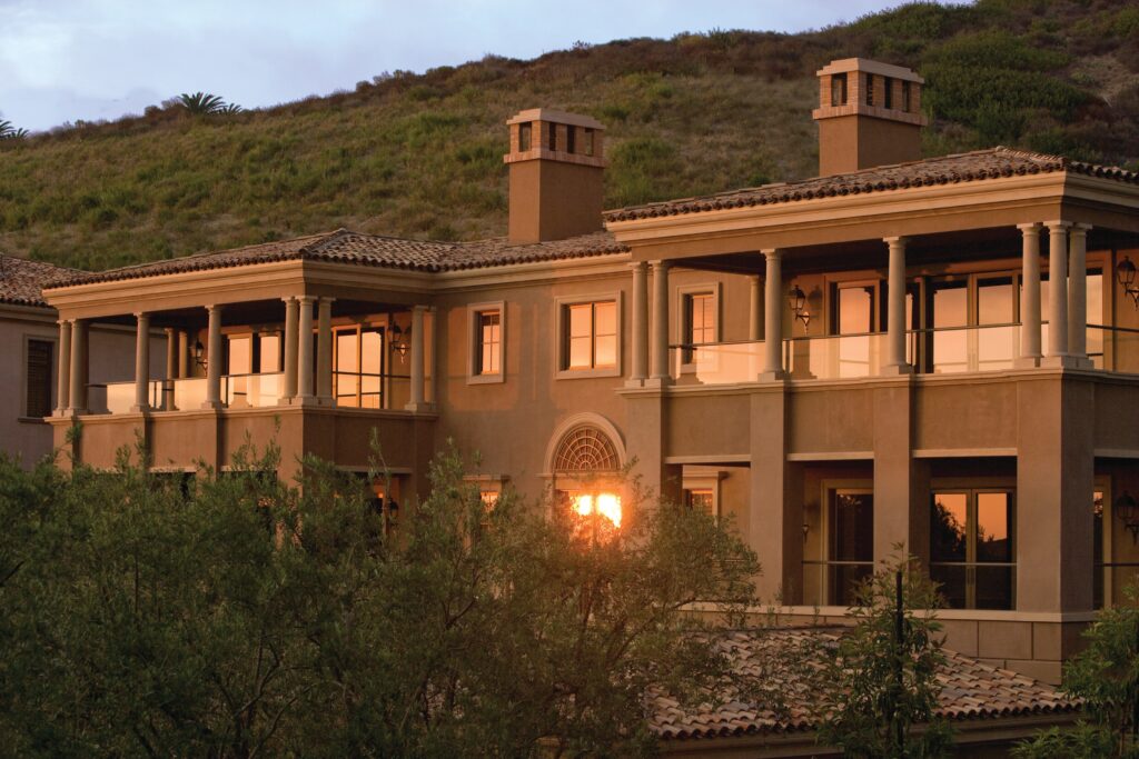 Tan stucco exterior of Pelican Hill Resort Inspirato residences in Newport Coast, California at golden hour.
