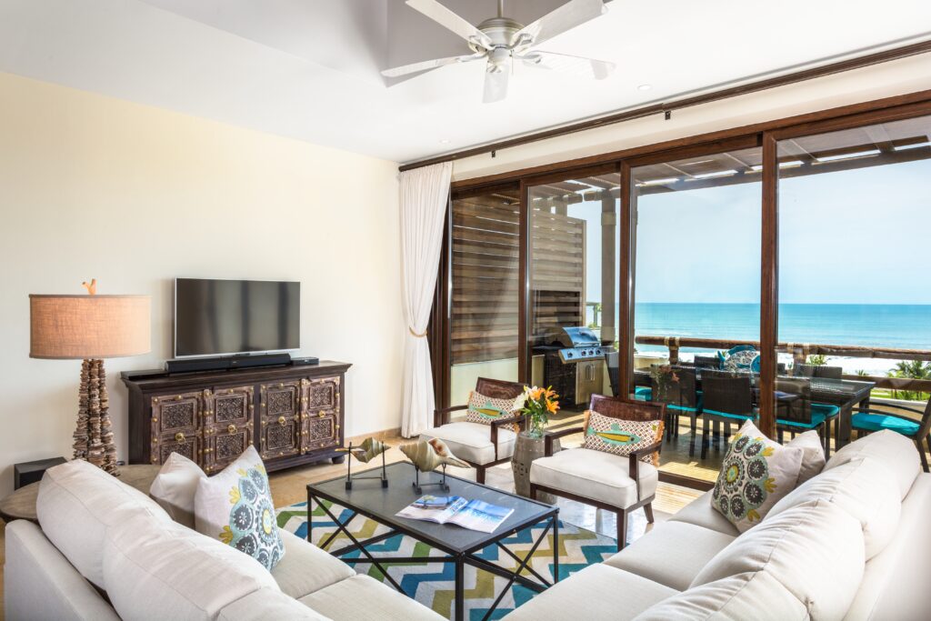 Bright and airy living area with a white couch, Mexican decor, and ocean views, in an Inspirato home in Los Veneros Resort, Punta de Mita.