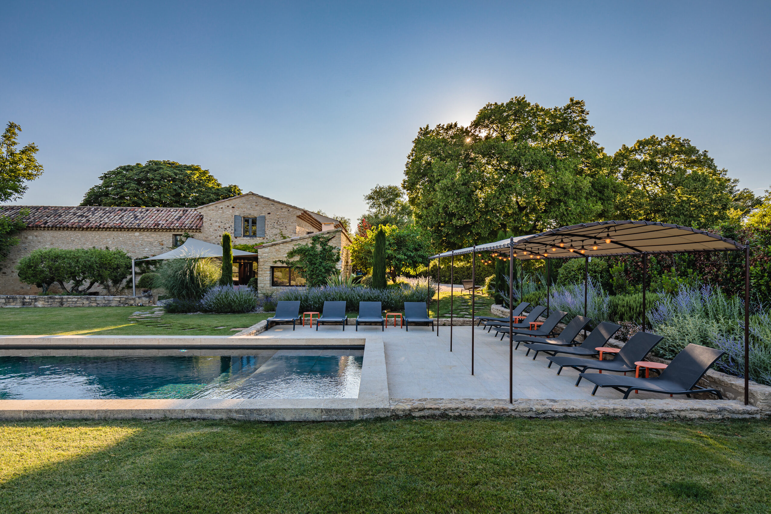 Backyard private pool and lounge area of a stone Inspirato luxury villa in Provence, France.