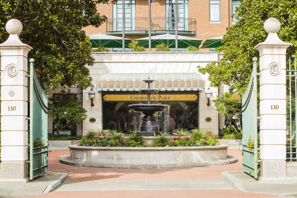 Gate entrance with roundabout and waterfall of The Charleston Place luxury hotel in Charleston's historic district during daytime.