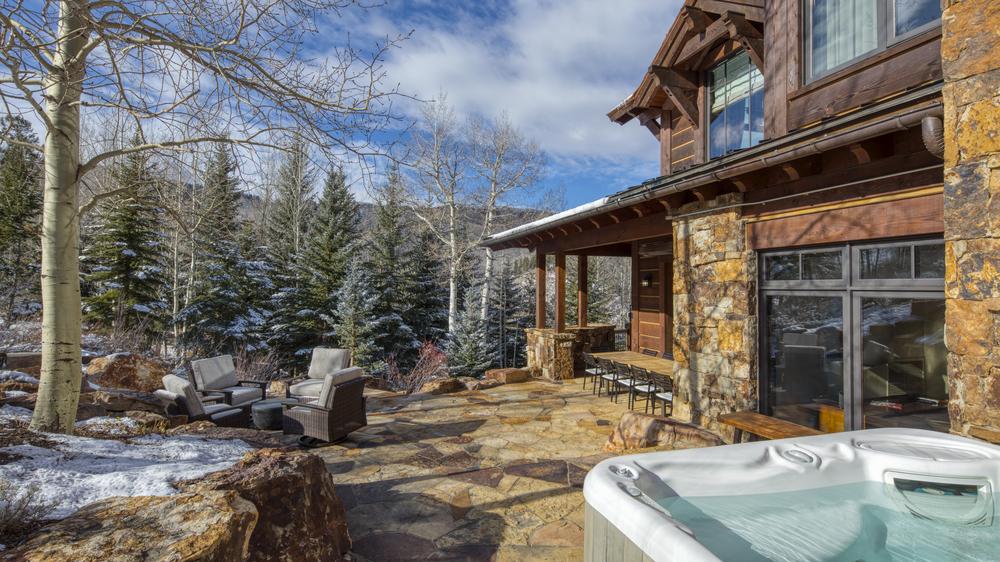 High Road outdoor stone patio area with lounge area with large chairs arranged in a circle and the hot tub off to the side.