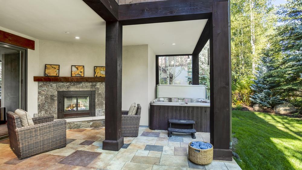 Bear Paw outdoor covered area with fireplace and two armchairs with the hot tub off to the side.