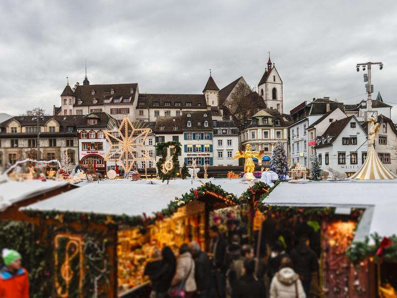 Christmas market during dusk with the lights illuminated in the stalls with a European town with white buildings