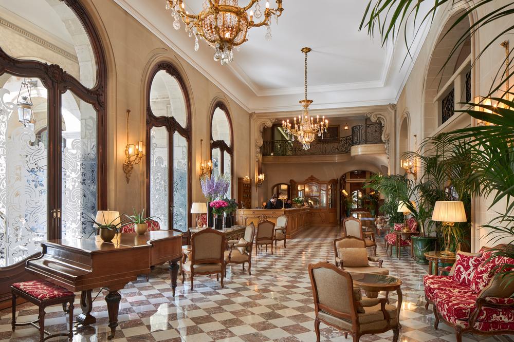 Hotel Regina lobby with high ceilings with chandelier and a grand piano.