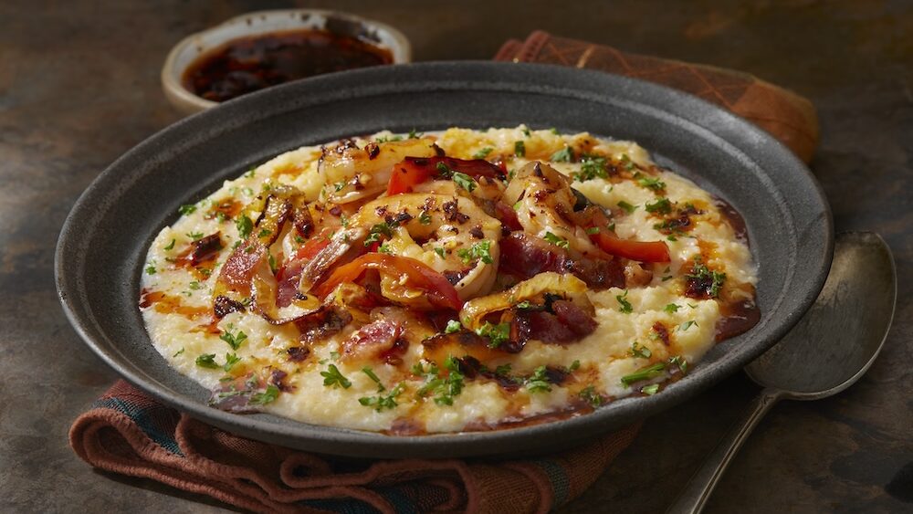 Shrimp and grits prepared in a black dish.