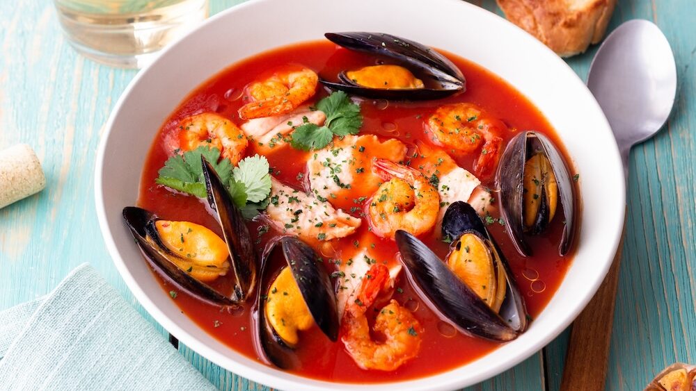 A bouillabaisse dish with a variety of seafood in a red sauce.