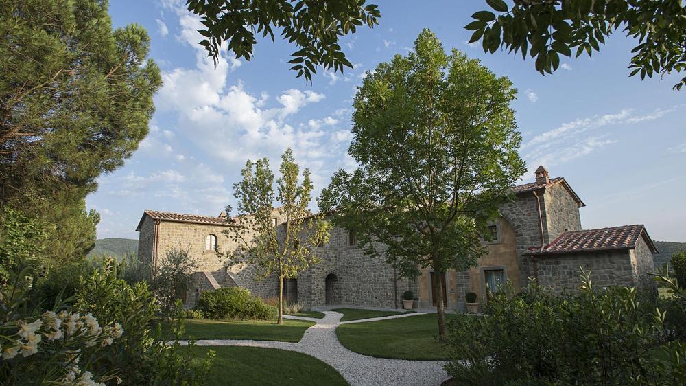 Exterior shot of La Corte dei Papi stone home with gravel pathways winding around the property.