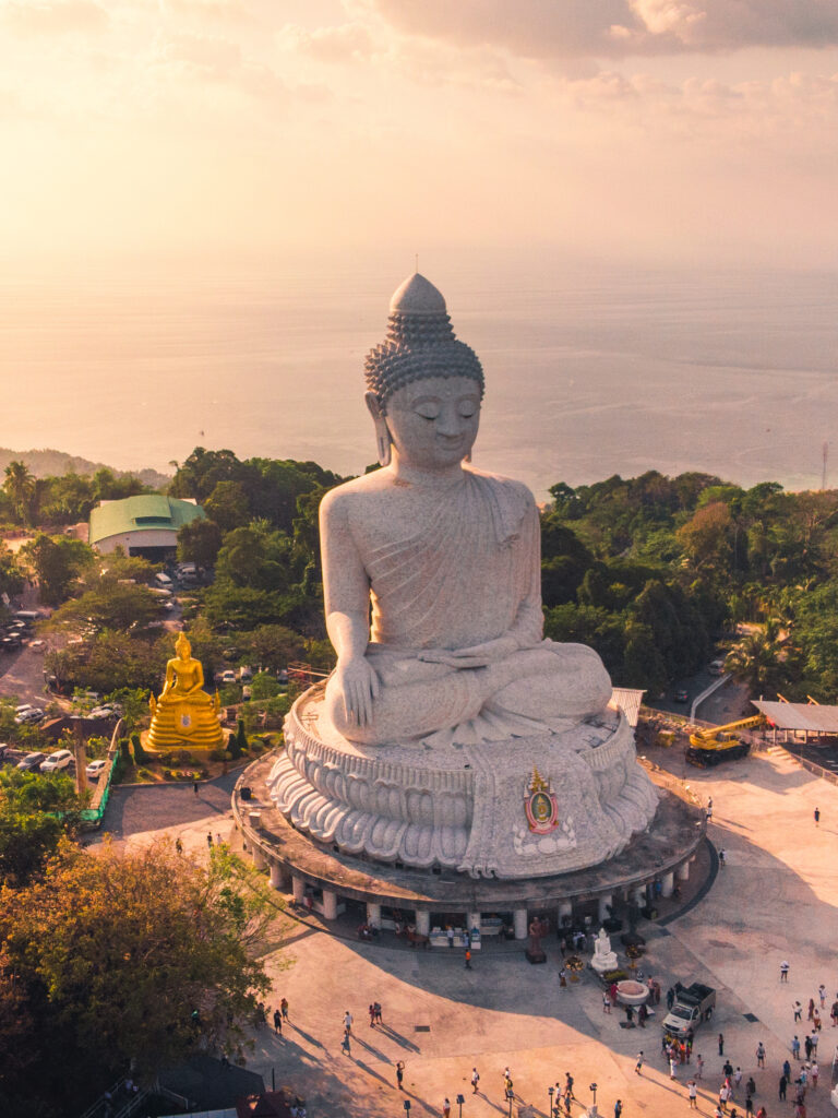 Aerial view of the majestic Big Buddha statue overlooking the coastline of Phuket at sunset.
