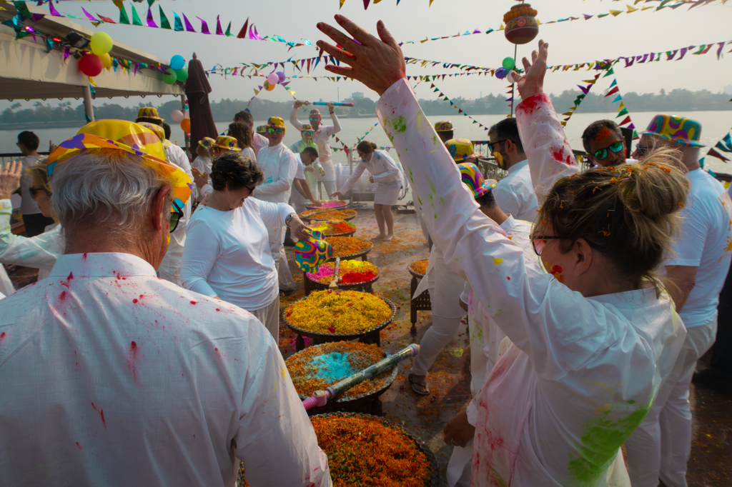 People celebrating and throwing up colorful dye in the air on a cruise ship in india