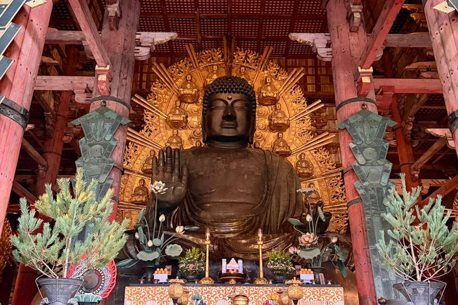 The Great Buddha (Daibutsu) statue inside Tōdai-ji Temple in Nara, Japan, framed by vibrant red wooden beams and golden halo detailing, symbolizing peace and spiritual reverence.