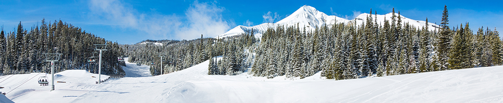 Snow-covered ski slopes and mountain peaks at Big Sky Resort in Montana surrounded by pine trees — an Inspirato luxury mountain getaway for adventure and relaxation.