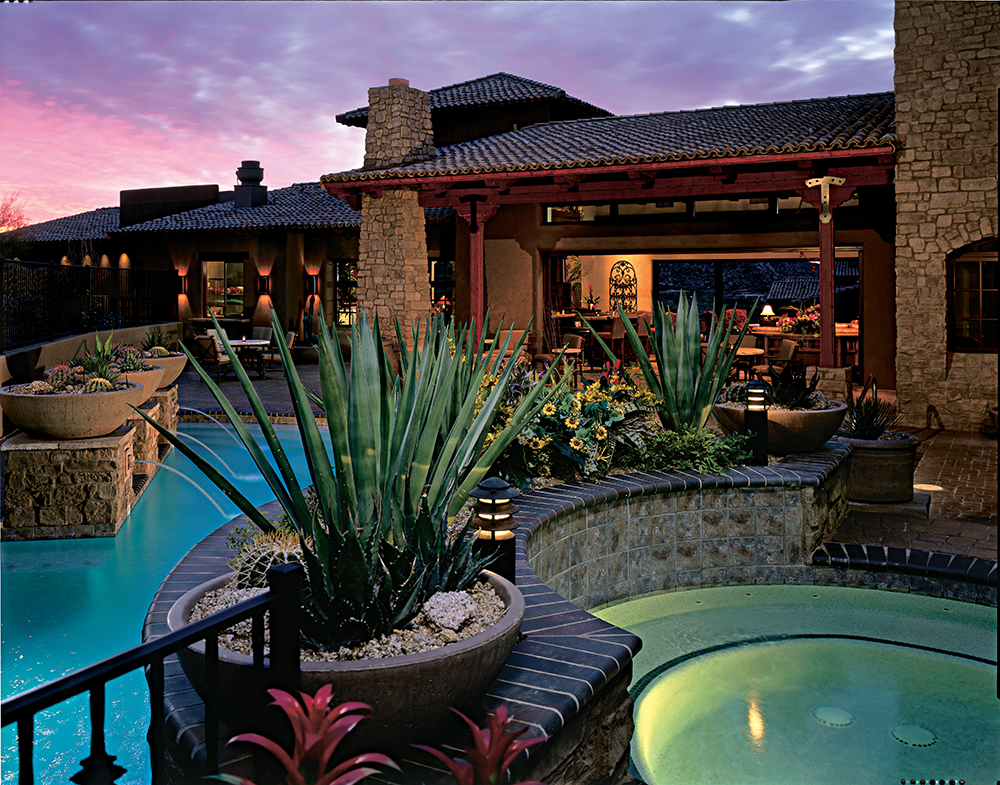 Luxury desert villa at sunset featuring a glowing pool, spa, and lush landscaping, offering a serene escape at an Inspirato residence in Scottsdale