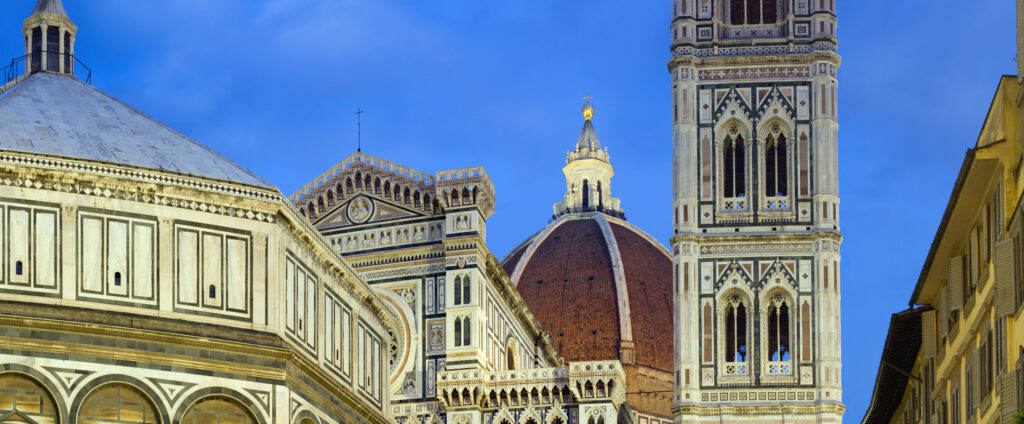 Evening view of Florence Cathedral and Giotto’s Bell Tower in Italy with Renaissance architecture glowing under blue skies — an Inspirato cultural travel destination for him.”
