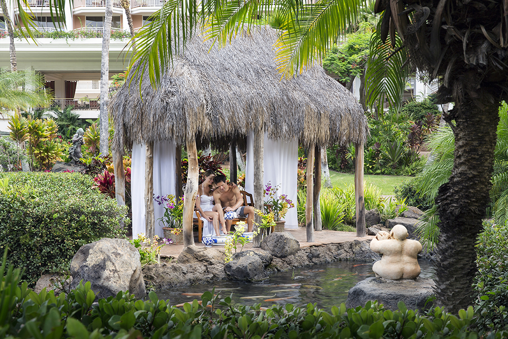 Couple relaxing in a private open-air cabana surrounded by tropical gardens at Ho‘olei at Grand Wailea in Maui — a luxury wellness retreat with spa experiences and tranquil scenery by Inspirato.