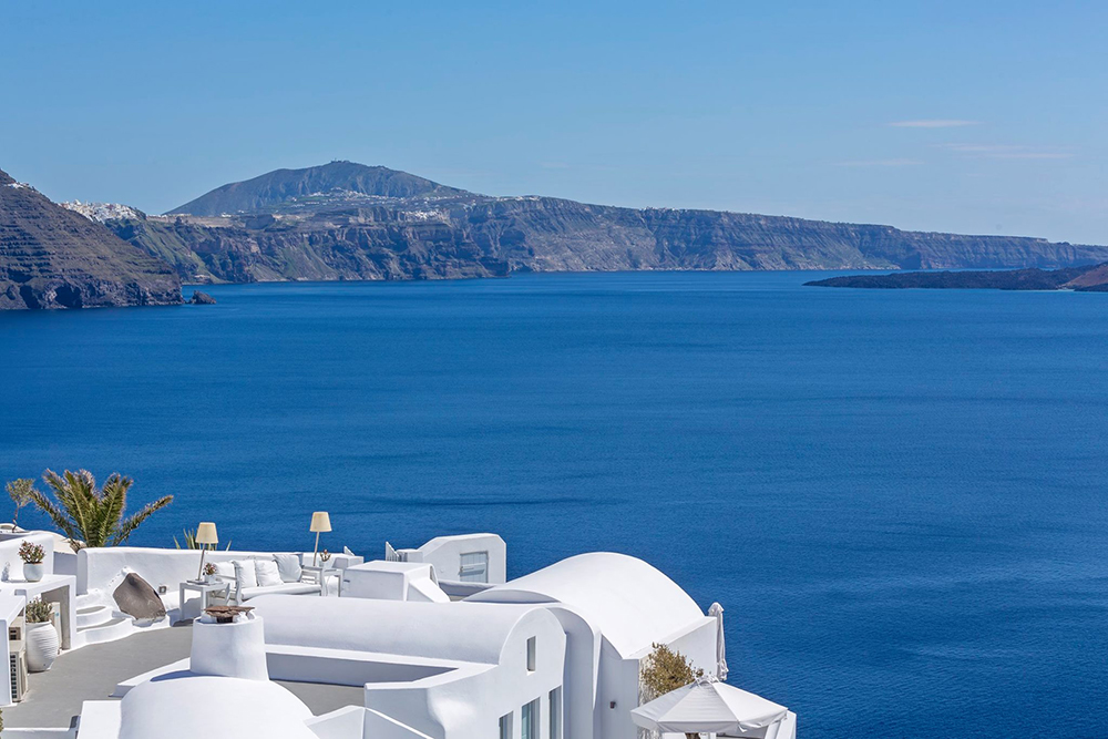 Whitewashed luxury suites perched above the caldera in Oia, Santorini, Greece, with panoramic Aegean Sea views—ideal for a romantic, film-inspired island escape.