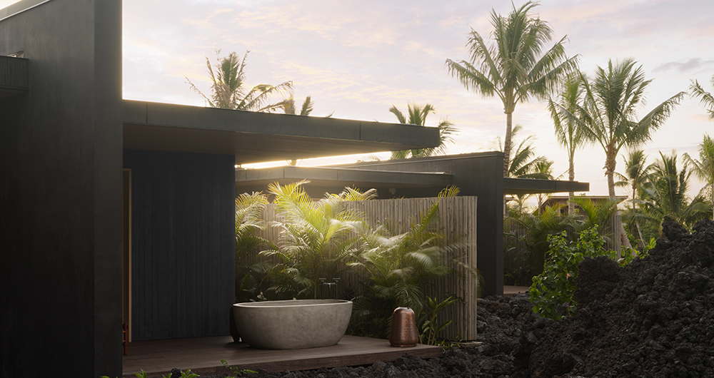 Outdoor soaking tub at a luxury wellness retreat surrounded by tropical palms and lava rock—peaceful setting for rejuvenation at an Inspirato destination