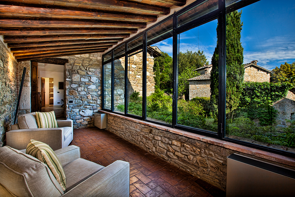 Charming stone-walled sunroom in a luxury Tuscan villa with garden views, rustic wood-beamed ceilings, and countryside scenery—perfect for a film-worthy Italian escape.
