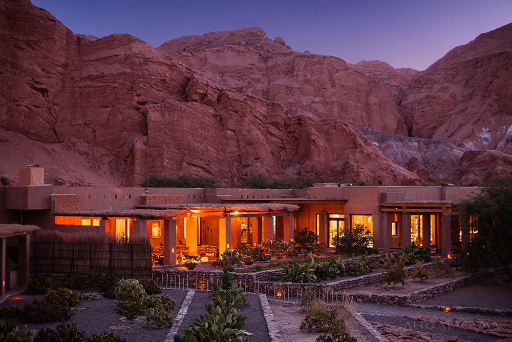 Alto Atacama Desert Lodge at dusk in the Atacama Desert, Chile, surrounded by dramatic red rock canyons and native gardens under a twilight sky