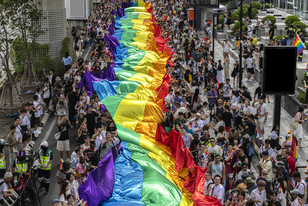 A vibrant rainbow flag ripples above a joyful crowd at a Pride parade, capturing the spirit of celebration, unity, and support for LGBTQ+ rights.