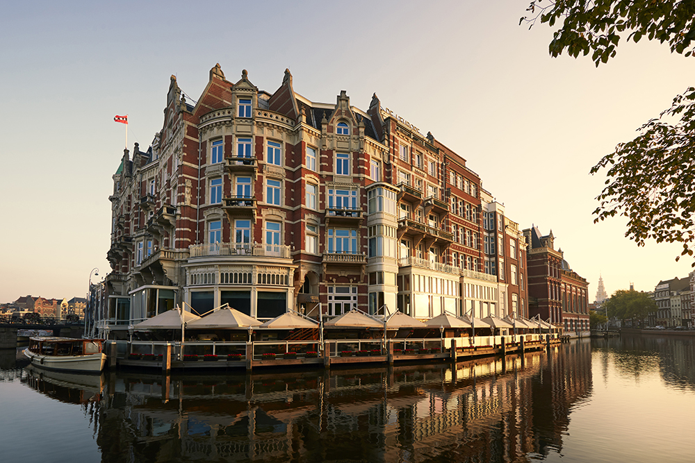 Historic canalfront façade of De L’Europe Amsterdam at sunset, a Three Michelin Key luxury hotel in the Netherlands featuring elegant suites, fine dining, and central access to Amsterdam’s cultural landmarks.
