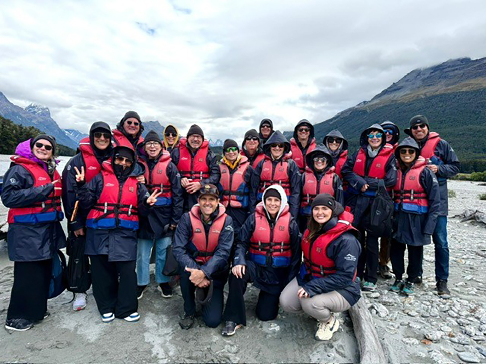 Inspirato members wearing red life jackets and rain gear pose for a group photo before a jet boat adventure along the Dart River in New Zealand’s Southern Alps.