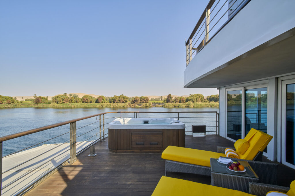 Private balcony suite aboard the Oberoi Philae featuring a hot tub and lounge chairs overlooking the Nile River in Egypt.