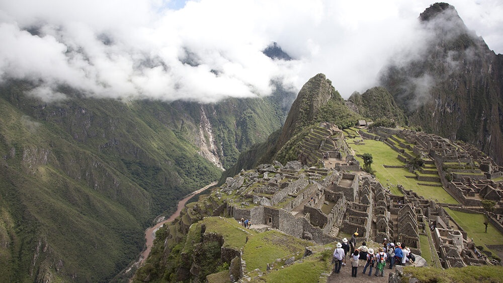 Machu Picchu’s ancient Incan terraces and stone ruins set high in the Andes Mountains, with clouds drifting over the surrounding valley in Peru.