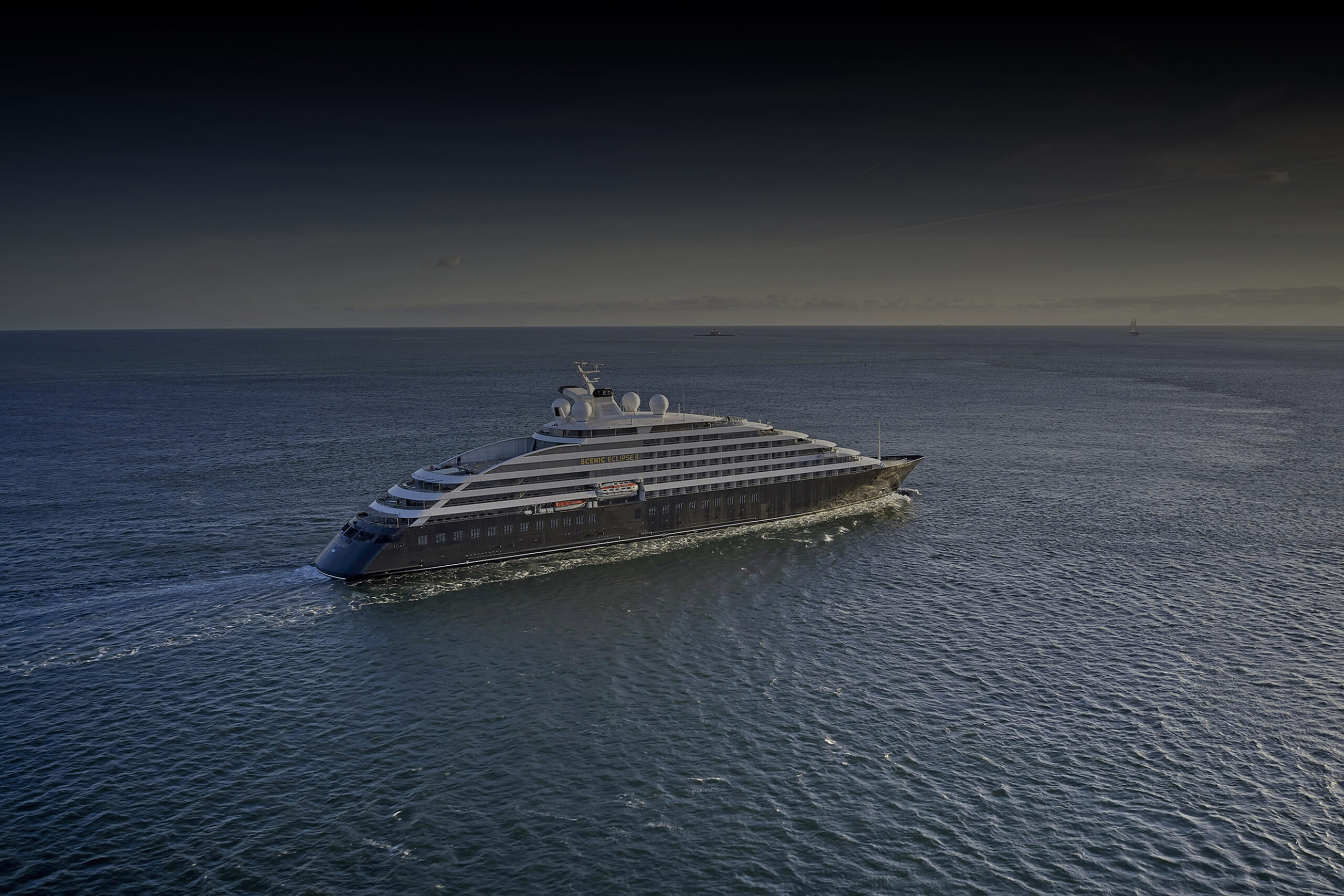Scenic Eclipse II sailing off the coast of Lisbon, Portugal, an ultra-luxury expedition yacht cruising across calm open ocean under a clear sky.