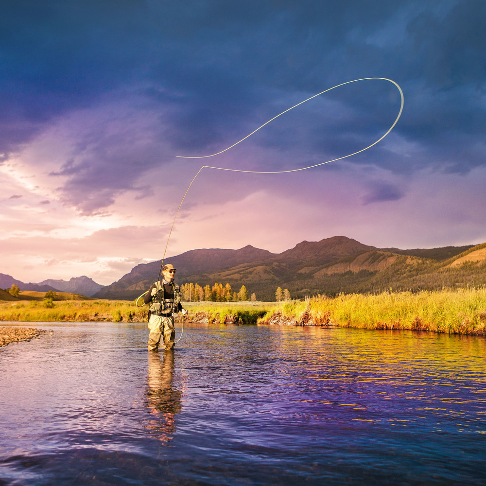 A man fly fishing in the middle of a quiet river in Big Sky
